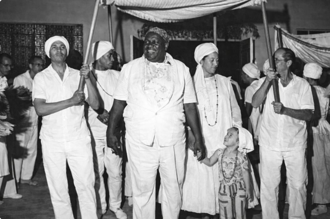 Cortejo histórico de umbandistas vestidos de branco, em preto e branco